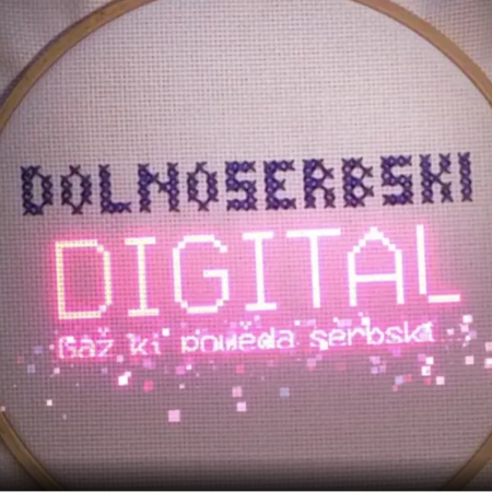 Stickrahmen mit gesticktem Schriftzug, der sagt: Dolnoserbski digital Gaž KI powěda serbski